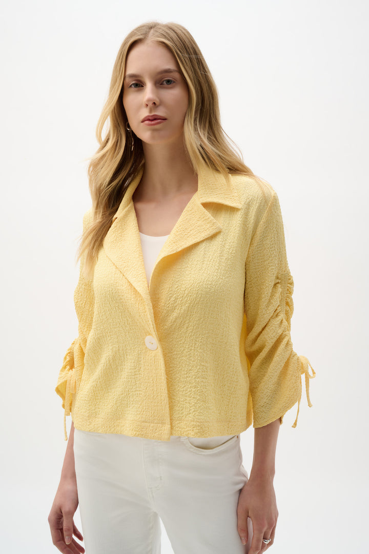 Woman wearing a yellow jacket over a white top on a white background