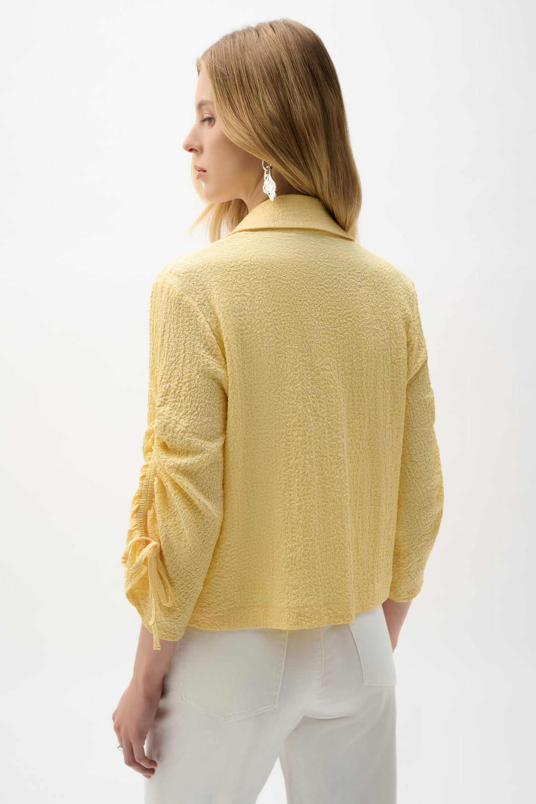 Woman wearing a yellow textured jacket on a white background