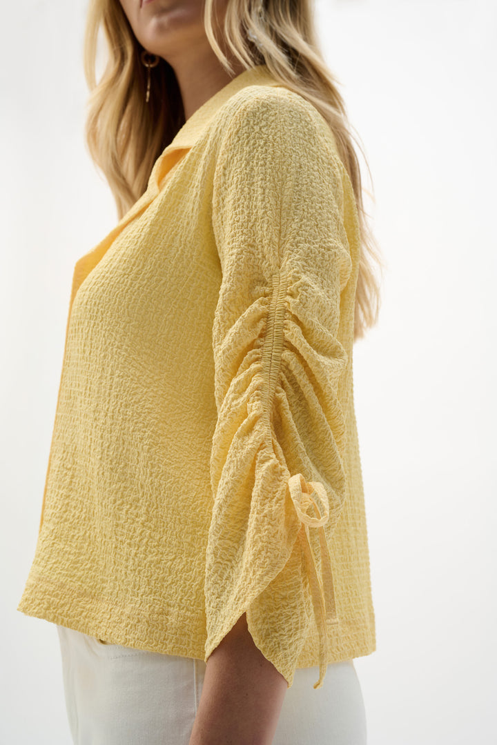 Yellow textured cardigan worn by a person on a white background