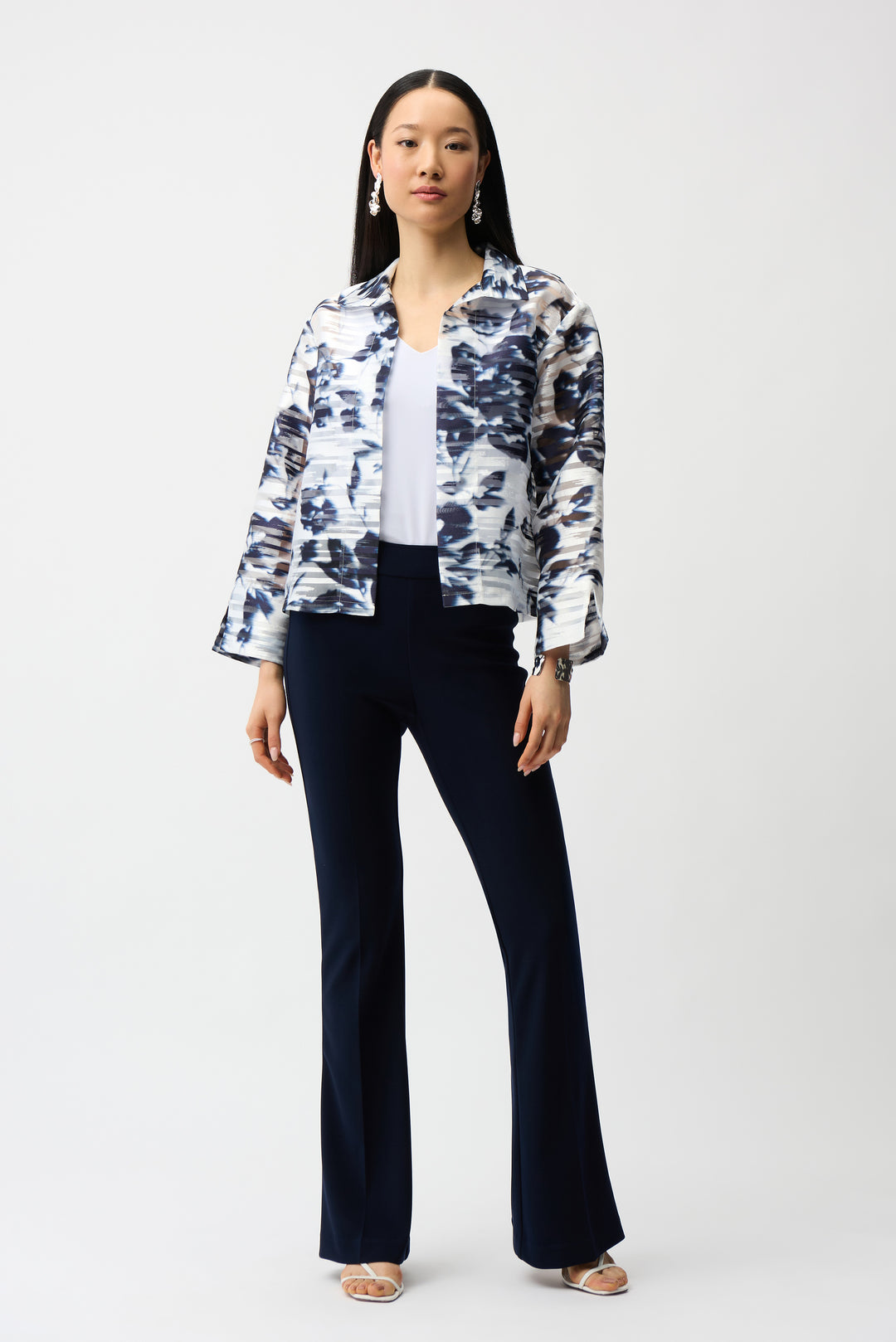 Woman wearing a floral shirt jacket and black pants on a white background