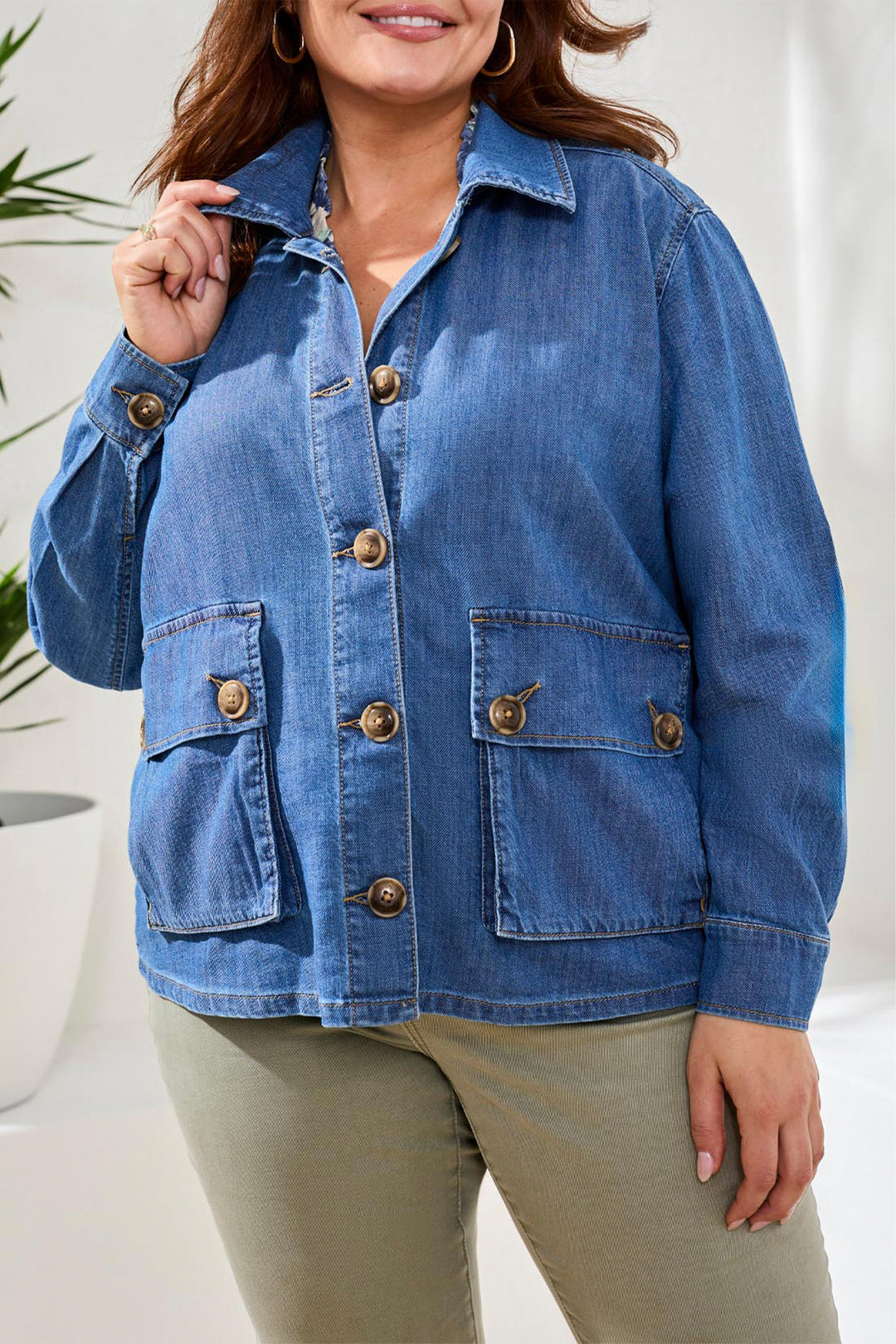 Woman wearing a blue denim jacket with gold buttons indoors.