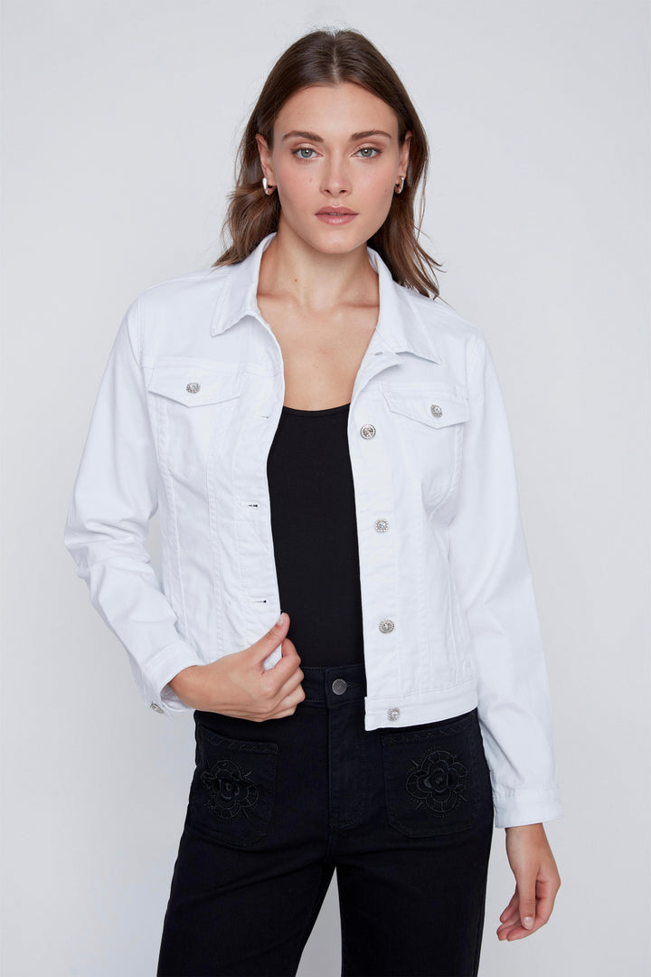 Woman wearing a white denim jacket over a black top on a plain background