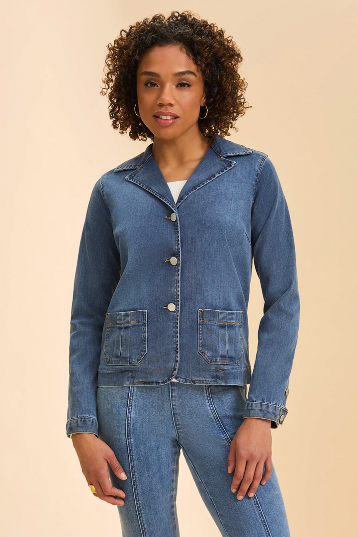 Woman wearing a blue denim blazer style jacket and jeans on a beige background