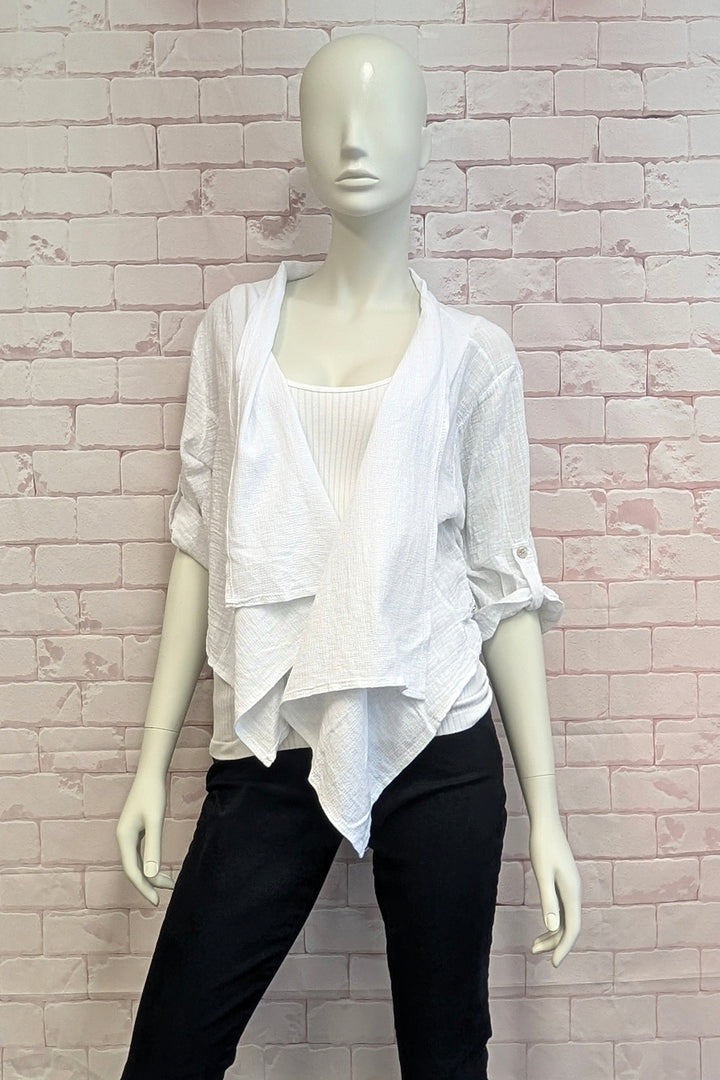 Mannequin wearing a white layered jacket and black pants against a light pink brick wall.