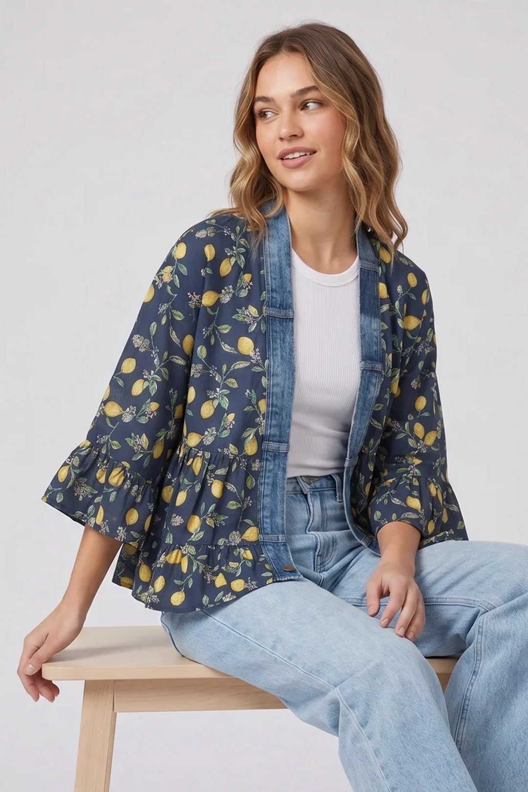 Woman wearing a navy kimono with yellow lemon pattern, sitting on a white background