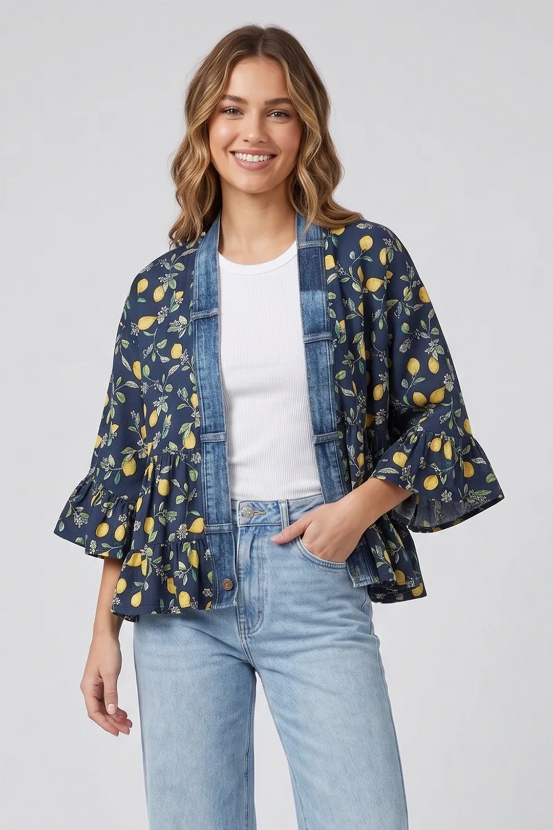 Woman wearing a lemon print kimono jacket and jeans on a white background