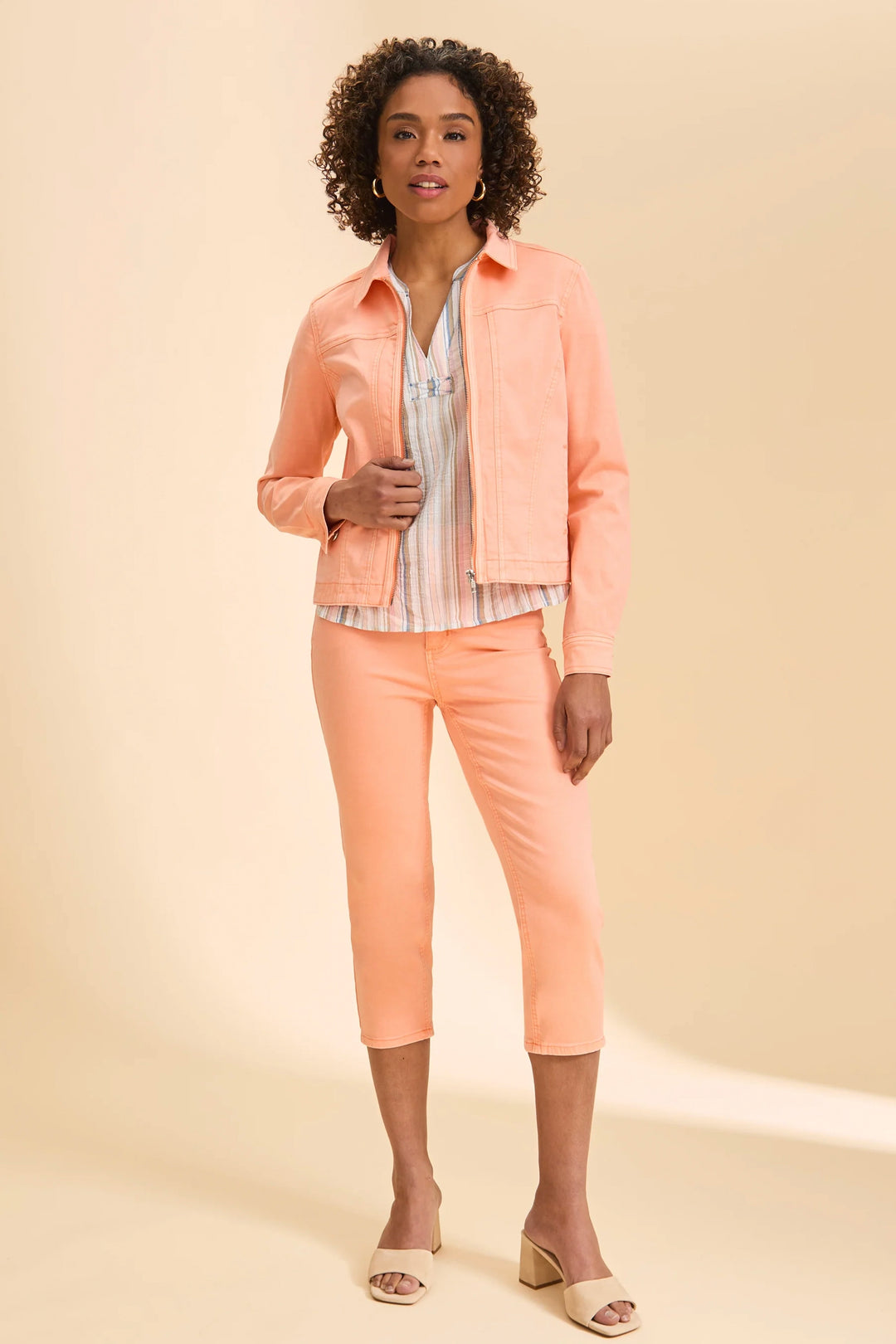 Woman wearing a peach jacket, shirt, and pants on a beige background
