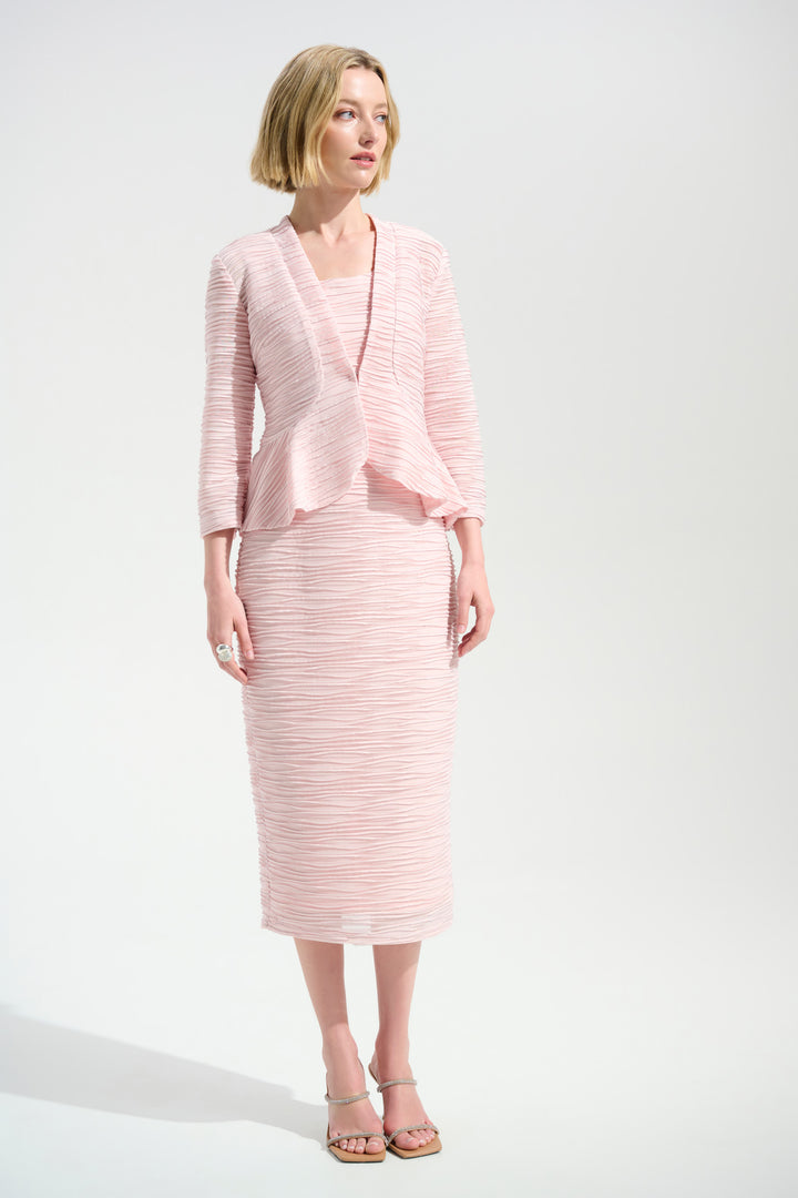 A woman modeling a light pink two-piece knit set consisting of a wrap-style jacket with three-quarter sleeves and a matching knee-length skirt, photographed against a plain light gray studio background.
