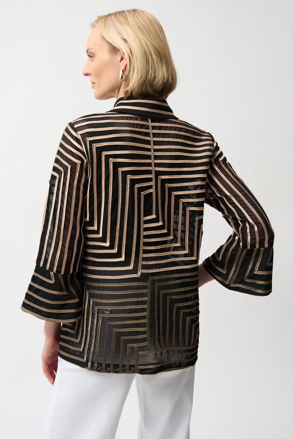Woman wearing a black and gold patterned jacket on a white background