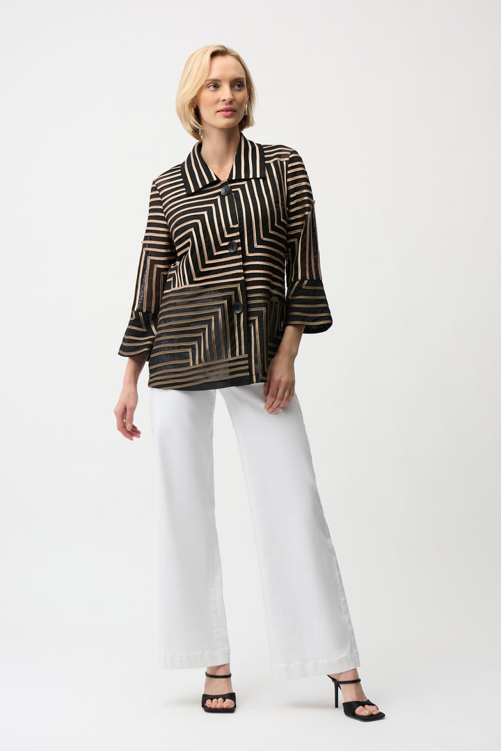 Woman wearing a black and gold patterned blouse with white pants on a white background