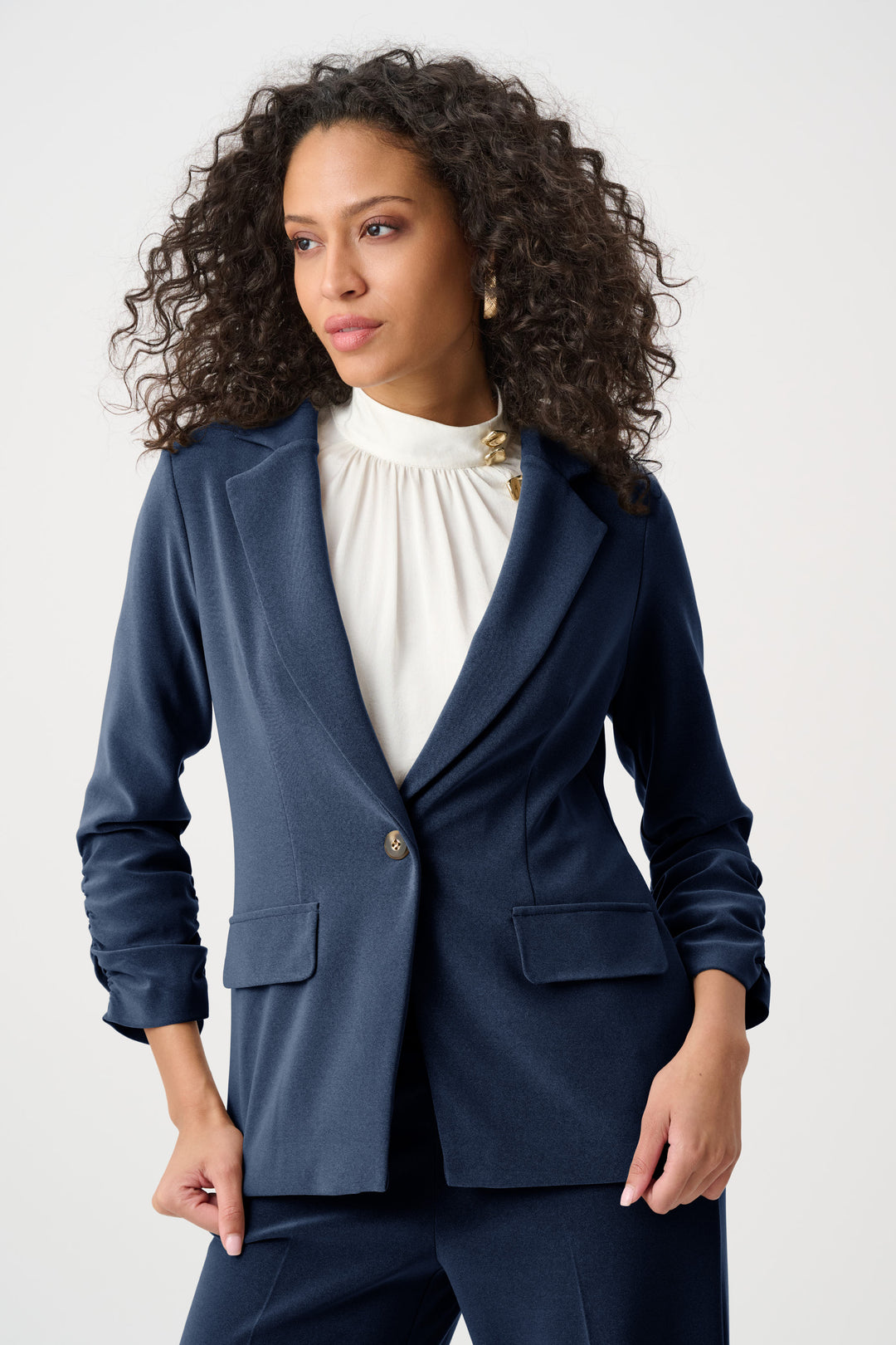 Woman wearing a navy blazer over a white top on a white background