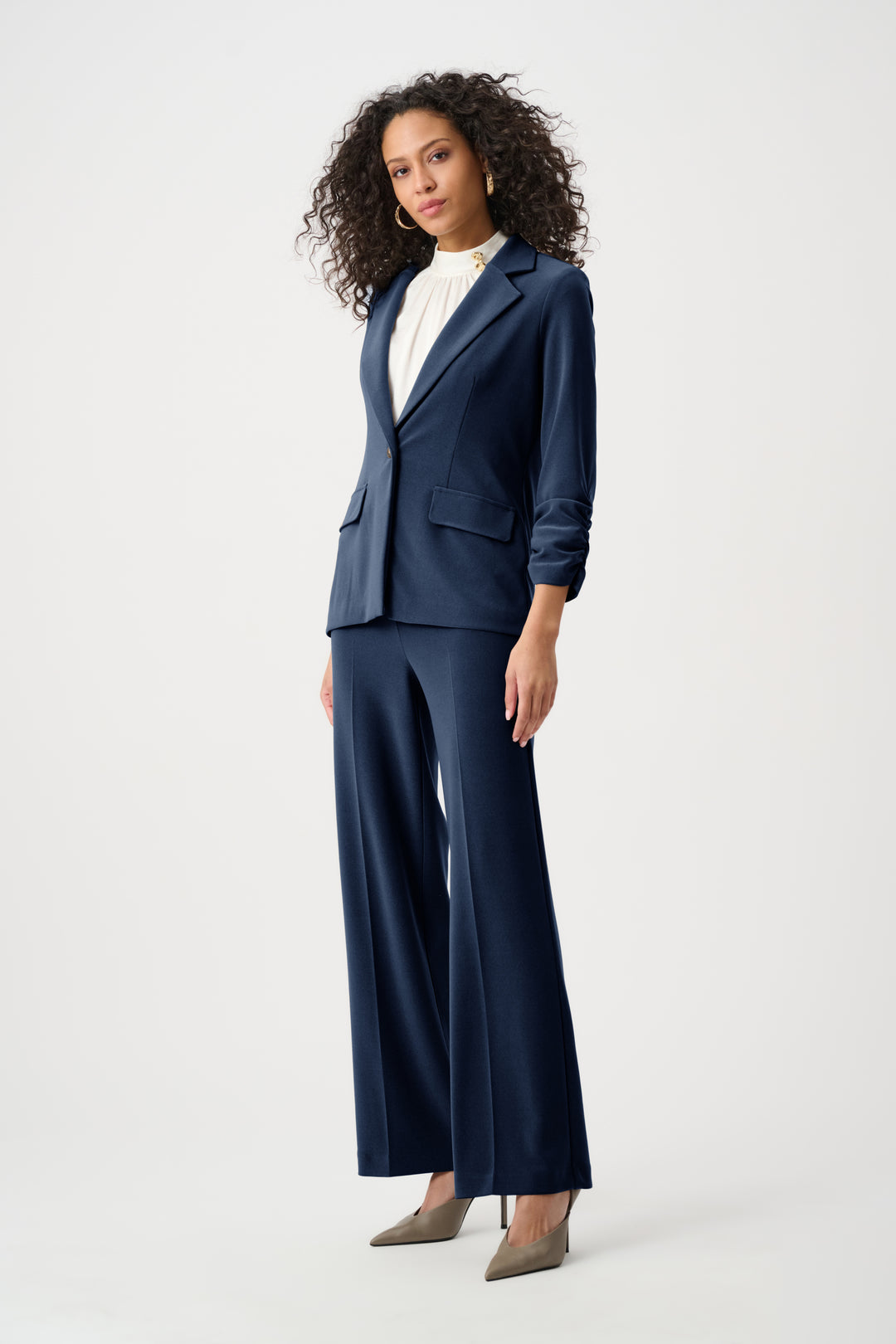 Woman wearing a navy blue suit with wide-leg pants on a white background