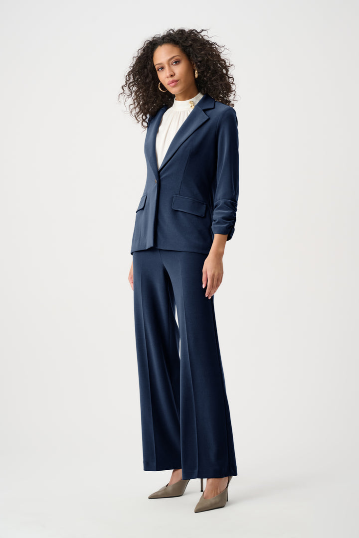 Woman wearing a navy blue suit with wide-leg pants on a white background