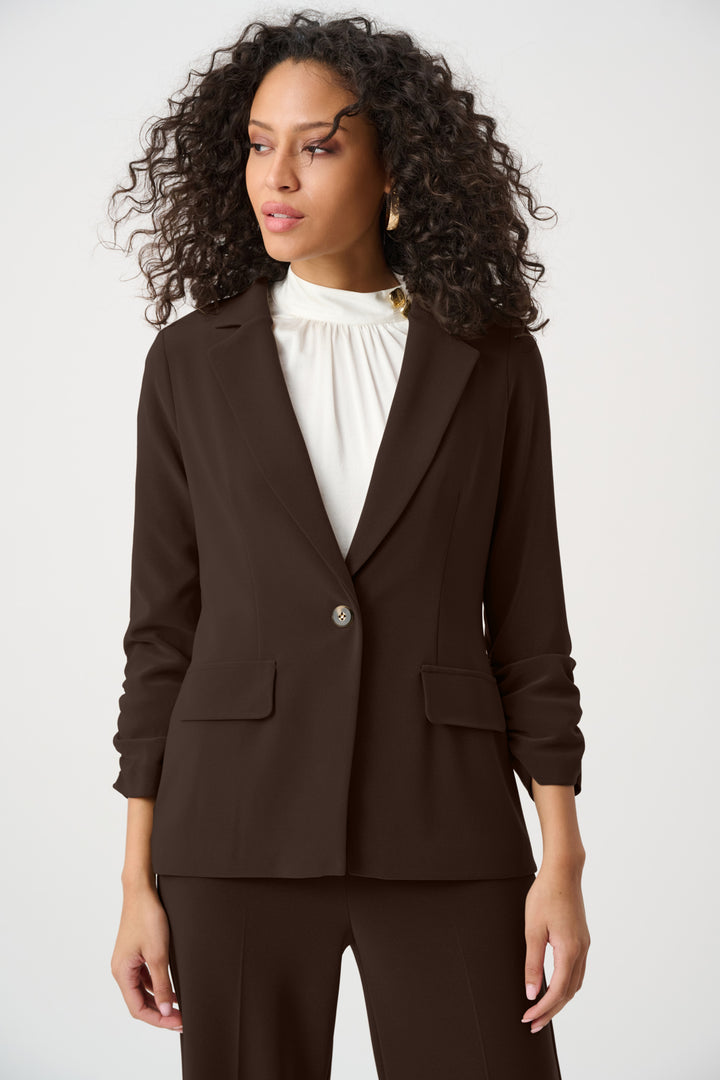 Woman wearing a brown blazer with a white blouse on a white background