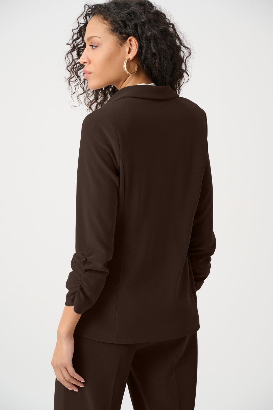 Woman wearing a brown long-sleeve blazer and pants on a white background