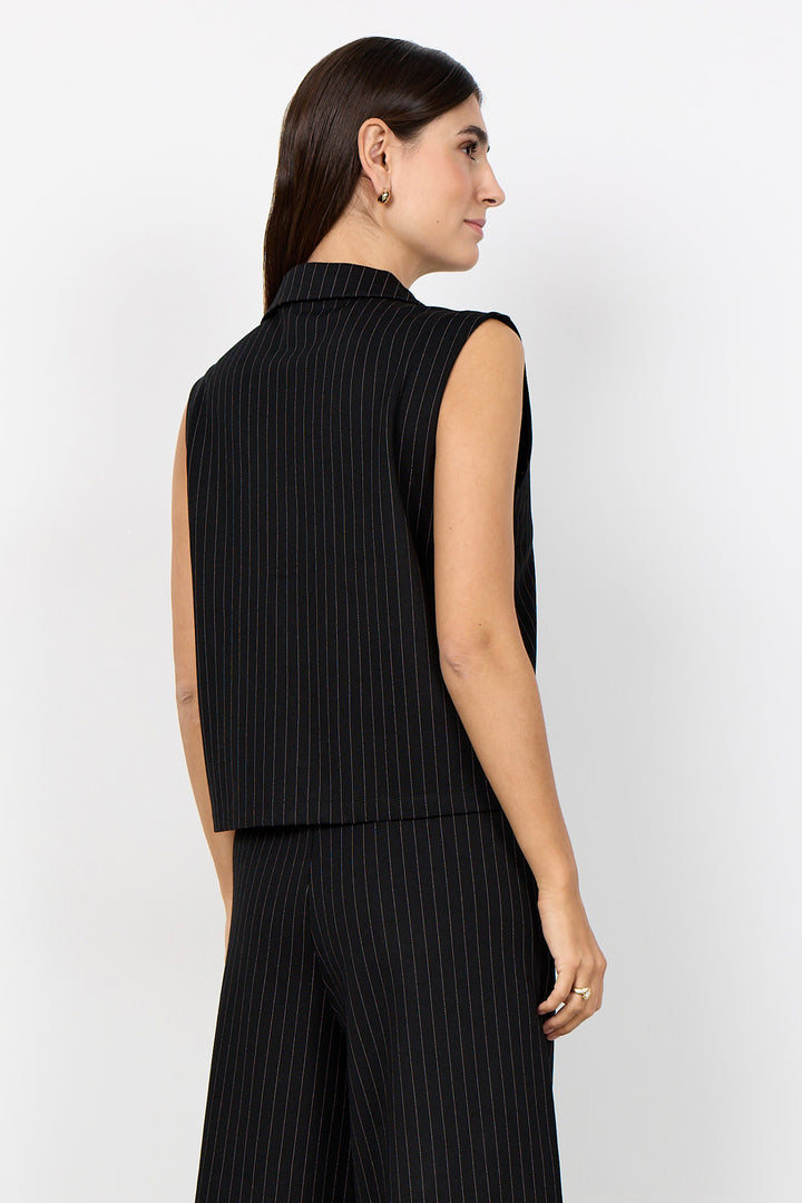 woman wearing a black pinstripe vest and matching pants on a  white background. 
