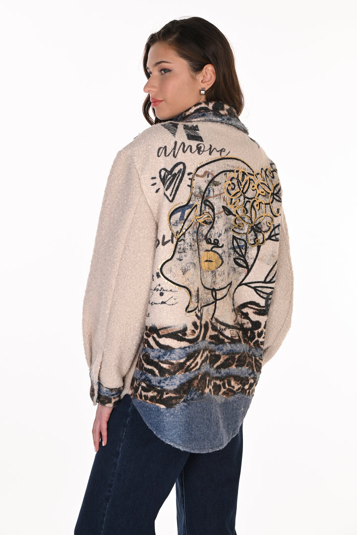 A woman shown from the back wearing a cream-colored fuzzy cardigan with a large graphic print featuring a stylized face, floral elements, and leopard print details, paired with dark blue jeans against a white background.