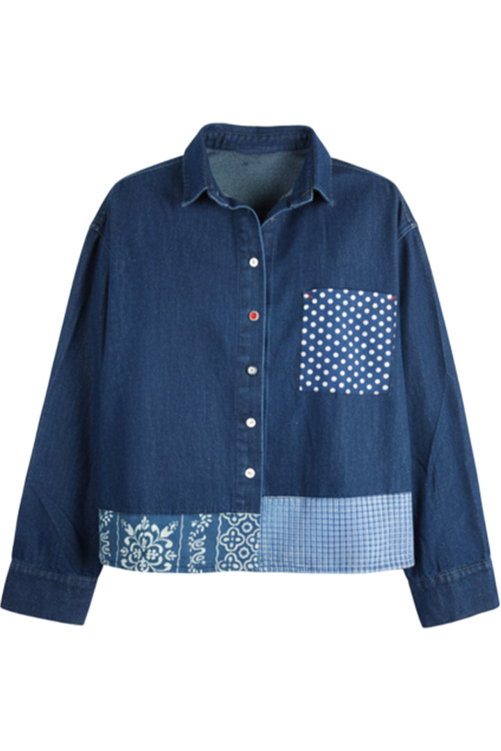 A blue denim patchwork button-up shirt with a patterned chest pocket and a decorative band of gingham, polka dots, and paisley at the hem, shown on a plain white background.