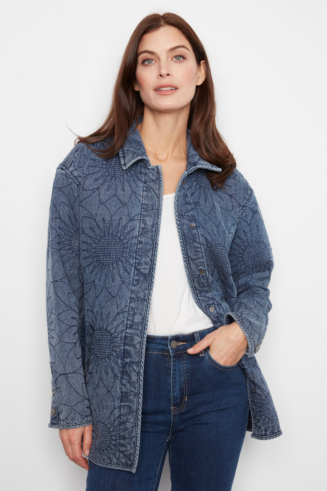 A woman modeling a blue textured, quilted jacket over a white top and dark blue jeans, photographed against a clean white studio background.