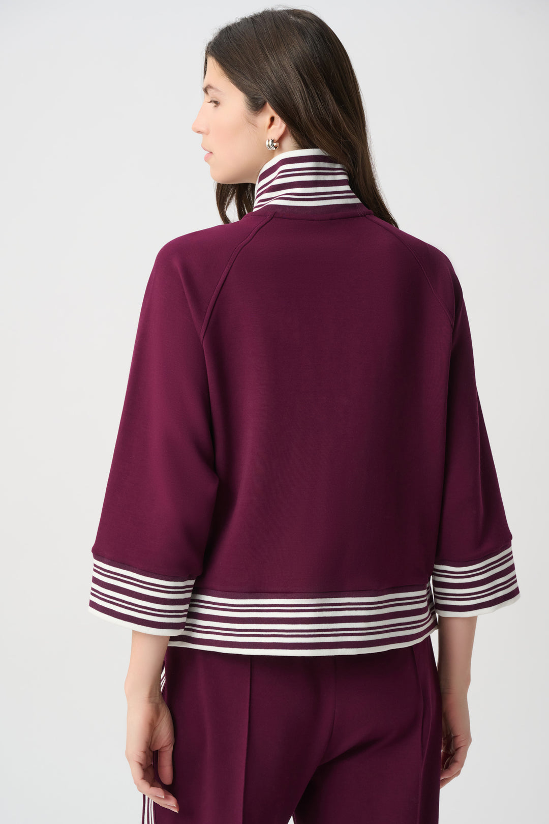 Person wearing a burgundy outfit with white stripes on a plain background