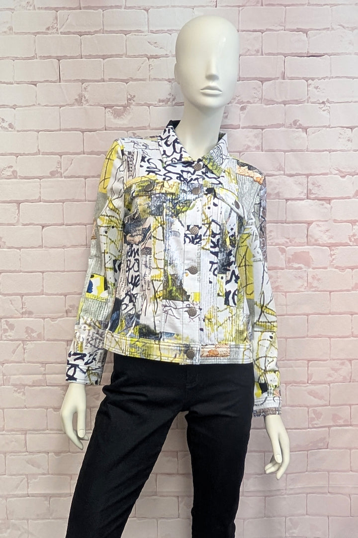 A long-sleeve button-up jacket with a busy graffiti-style abstract print in yellow, black, white, and gray, displayed on a white mannequin torso against a pink brick wall.