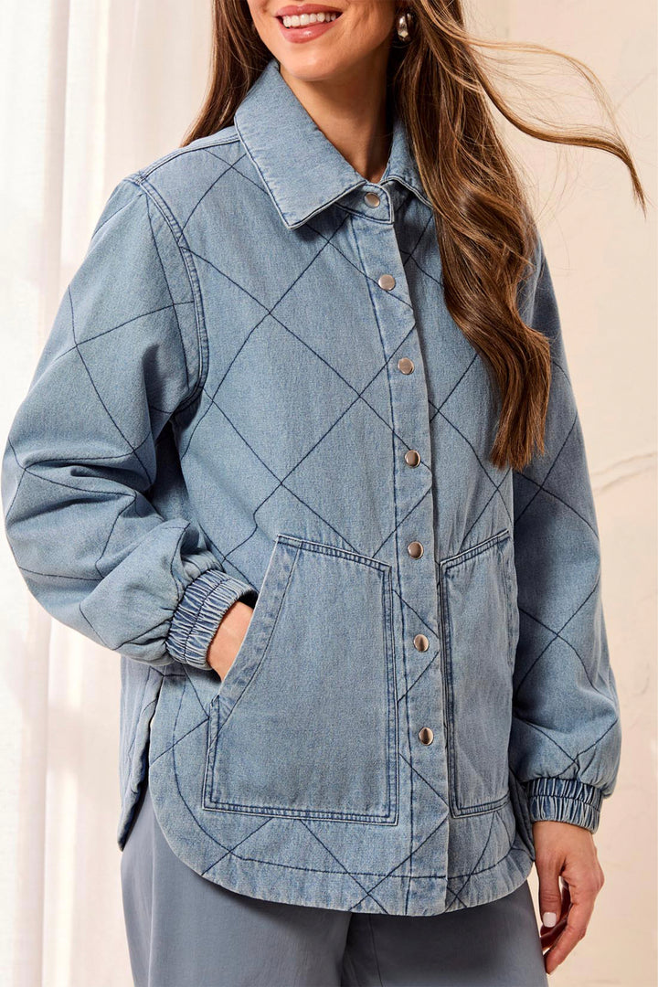 A woman wearing a light blue denim jacket with a diamond quilted pattern, featuring a button-up front, collar, and front pockets.