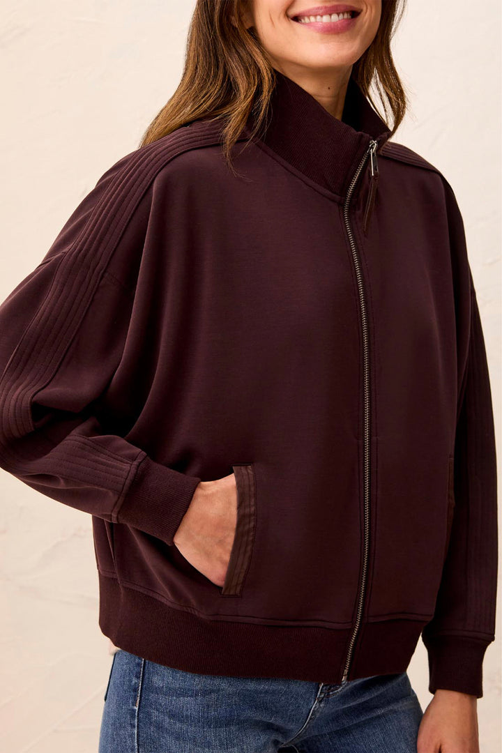 Person wearing a dark brown zip-up hoodie with a plain background