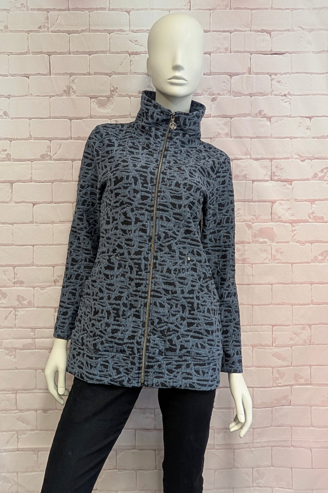 Mannequin wearing a zip jacket in front of a pink brick wall