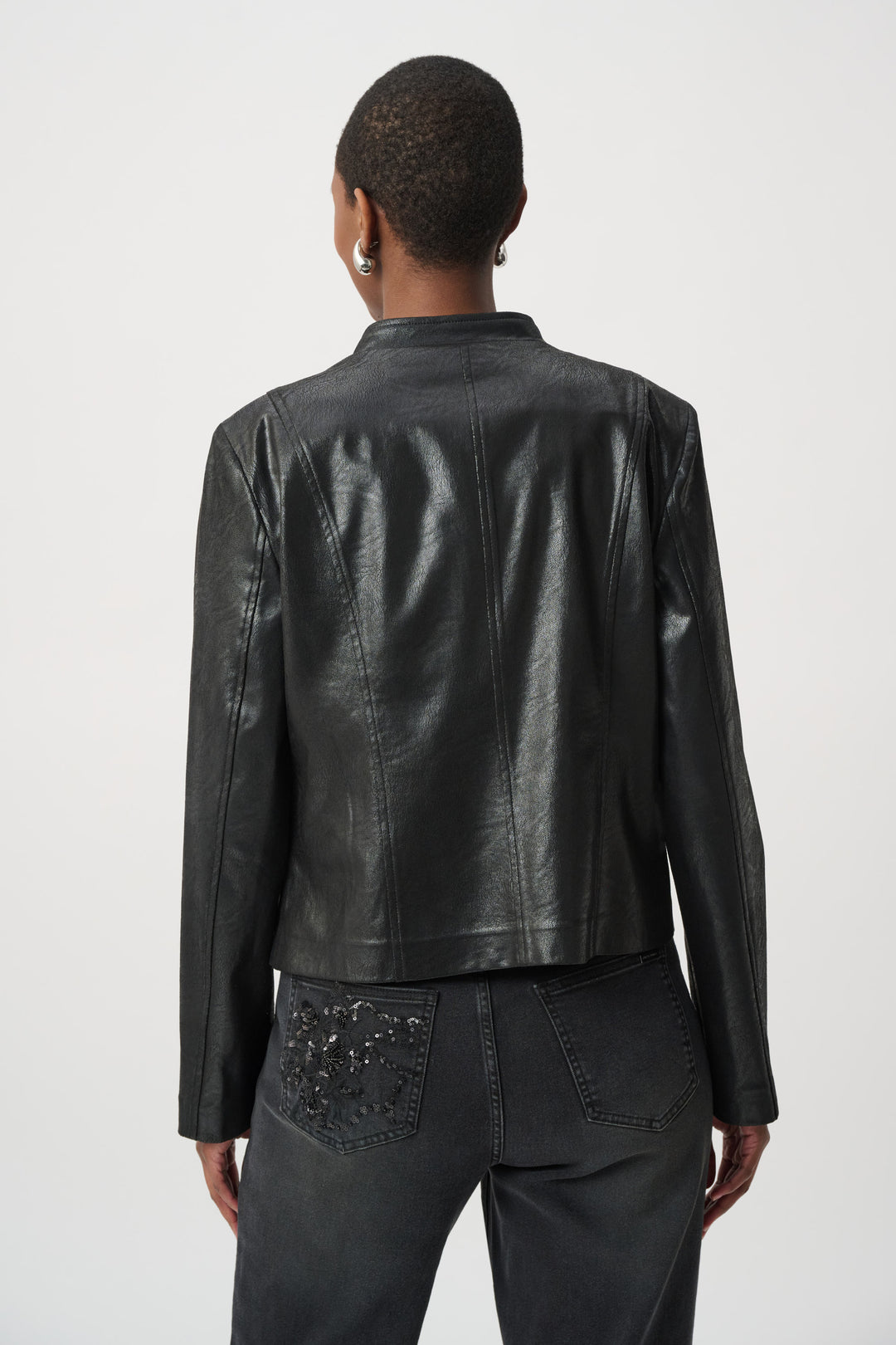 Woman shown from the back wearing a black leather jacket with floral embellishments on a white background