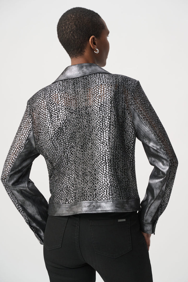 A woman shown from the back wearing a dark silver moto style jacket, and black pants in front of a white background. 