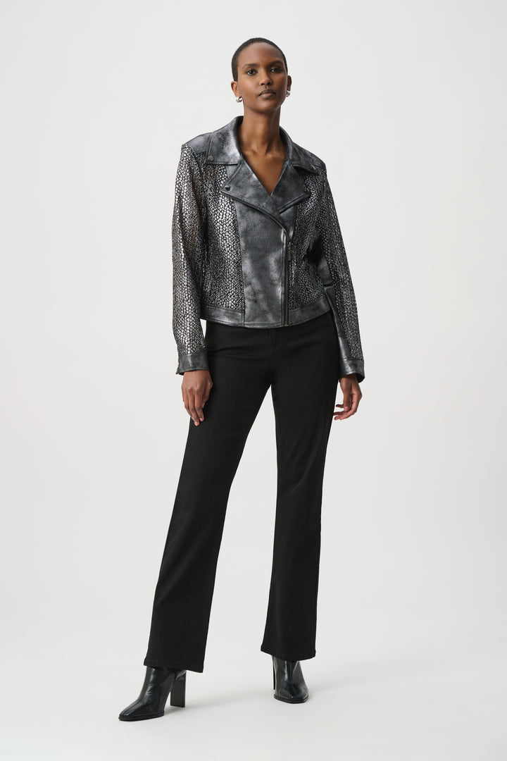 A woman wearing a dark silver moto style jacket, and black pants in front of a white background. 