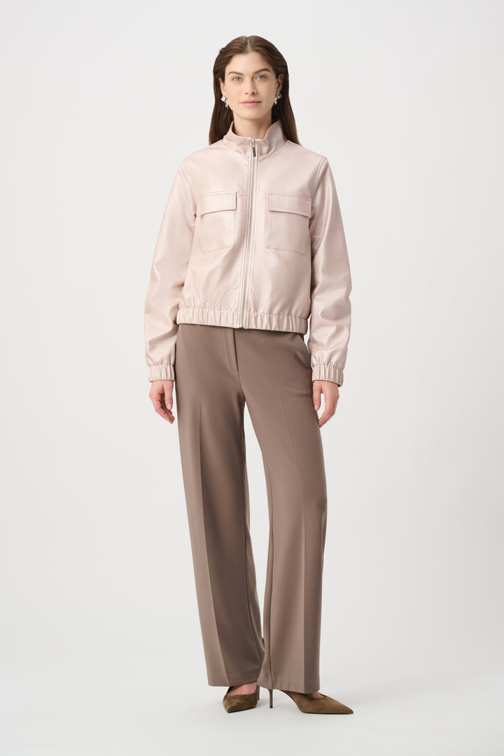 Woman wearing a light pink jacket and beige pants on a white background