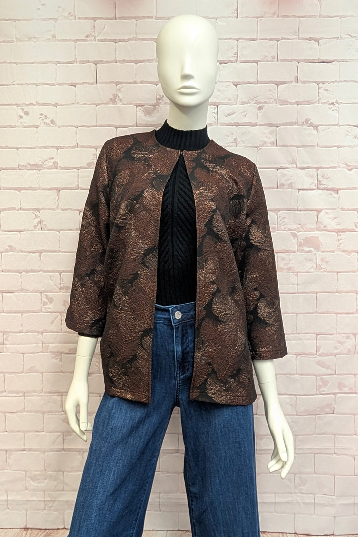 A mannequin standing in front of a brick background modelling a brown three-quarter sleeve jacket with a metallic feather print. 