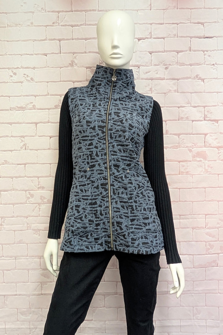 A female mannequin wearing a sleeveless zip-front vest with a high mock neck collar, featuring an abstract black and gray pattern.