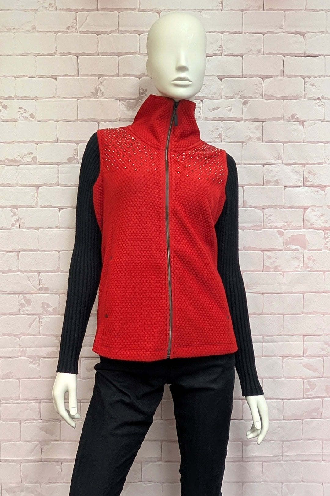 A mannequin wearing a red sleeveless vest with a high mock neck