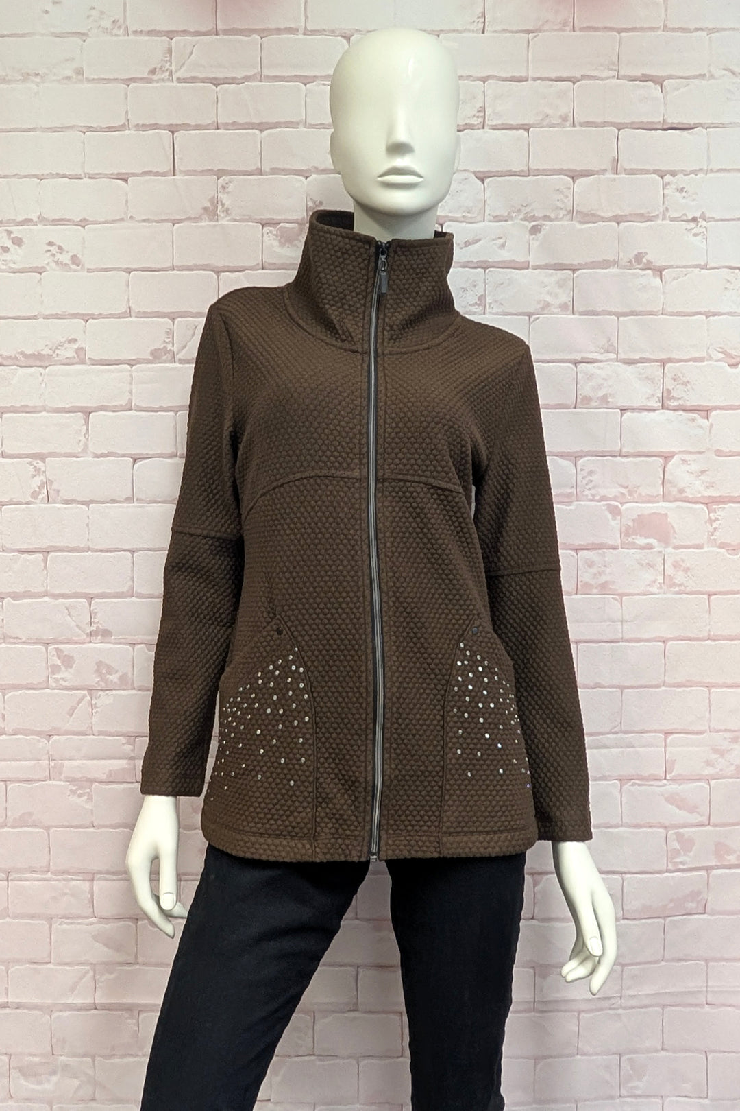 A mannequin wearing an off-white textured zip-up jacket with a high stand collar and decorative rhinestone patterns on the lower front