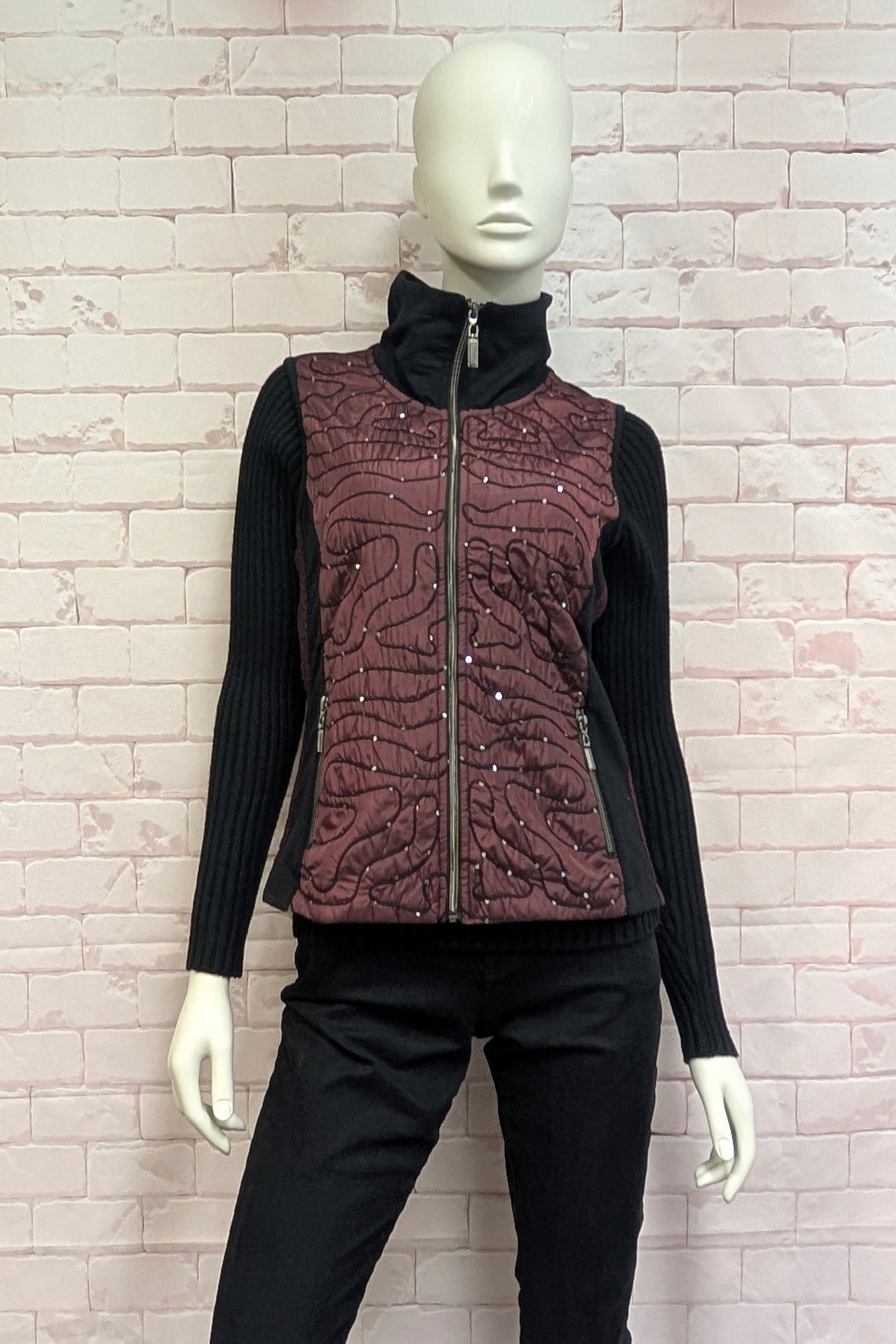 A mannequin wearing a women's burgundy and black vest in front of a white background. 