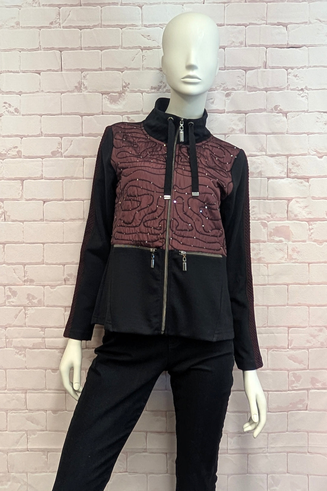 A mannequin wearing a women's black and burgundy zip jacket