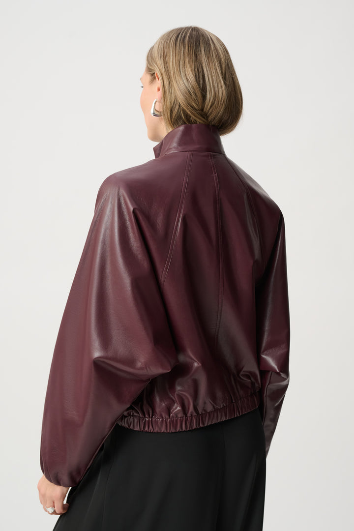 Person wearing a maroon leather jacket on a white background