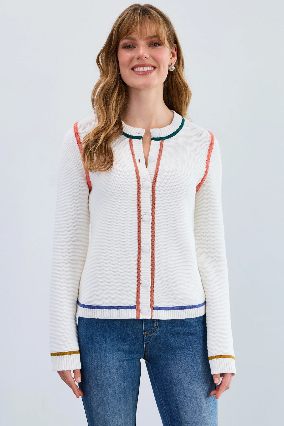 Woman wearing a white cardigan with colorful accents on a plain background