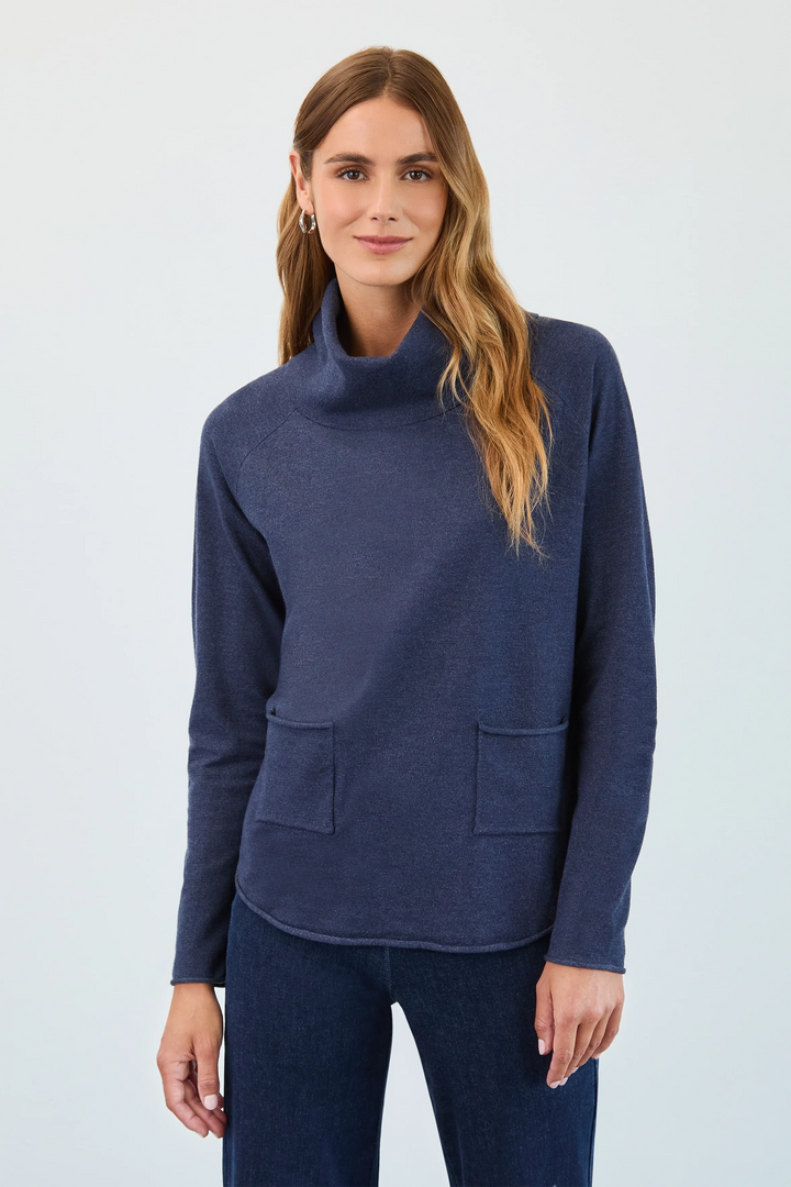 Woman wearing a blue cowl-neck sweater against a light gray background