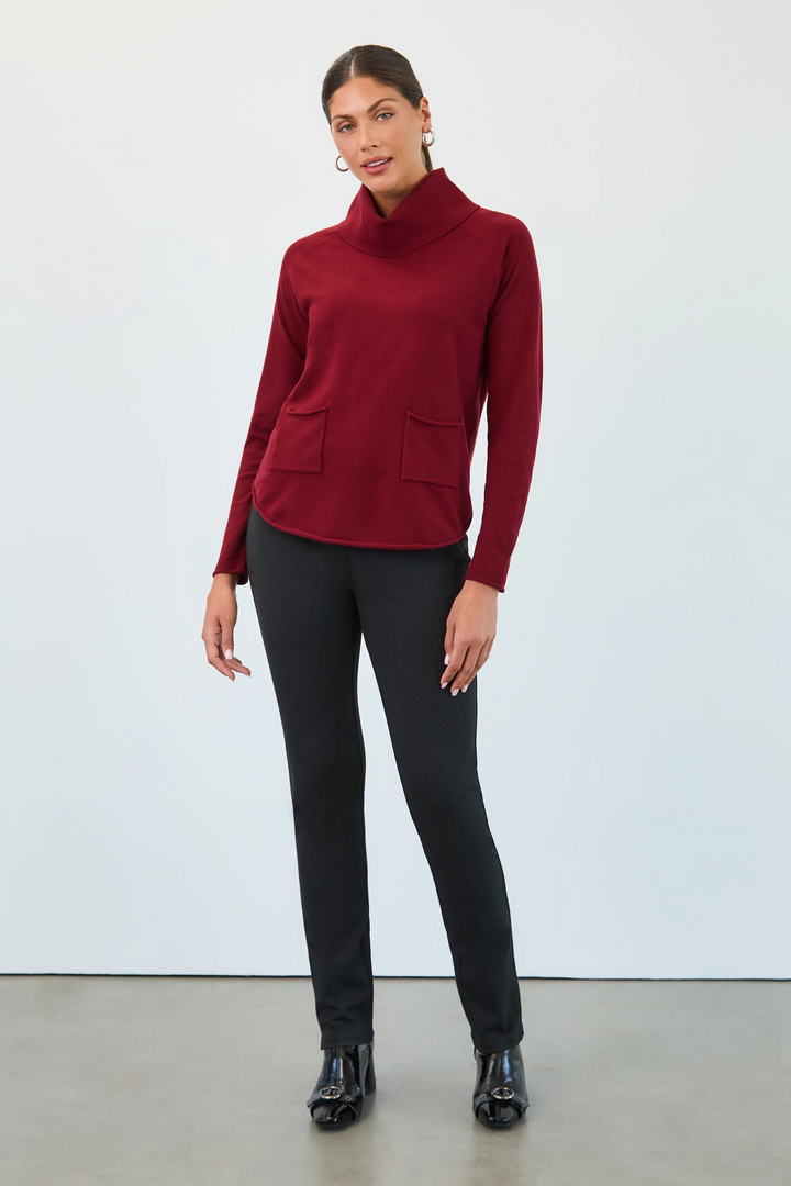 Woman wearing a red turtleneck sweater and black pants against a white background