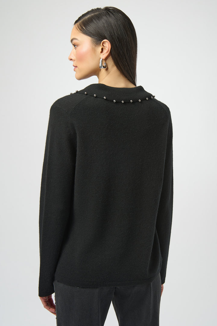 Black sweater with decorative elements on the collar on the back worn by a person against a white background