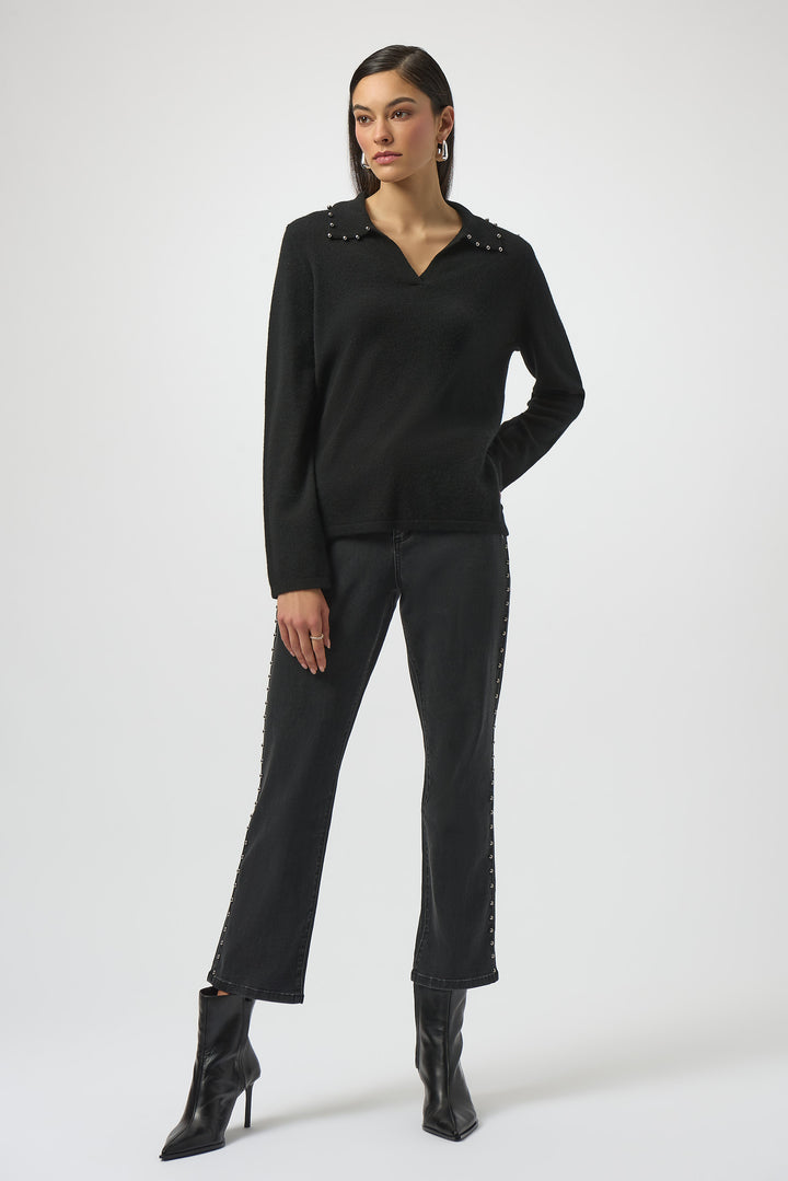 Woman wearing a black sweater top with studded details on a white background