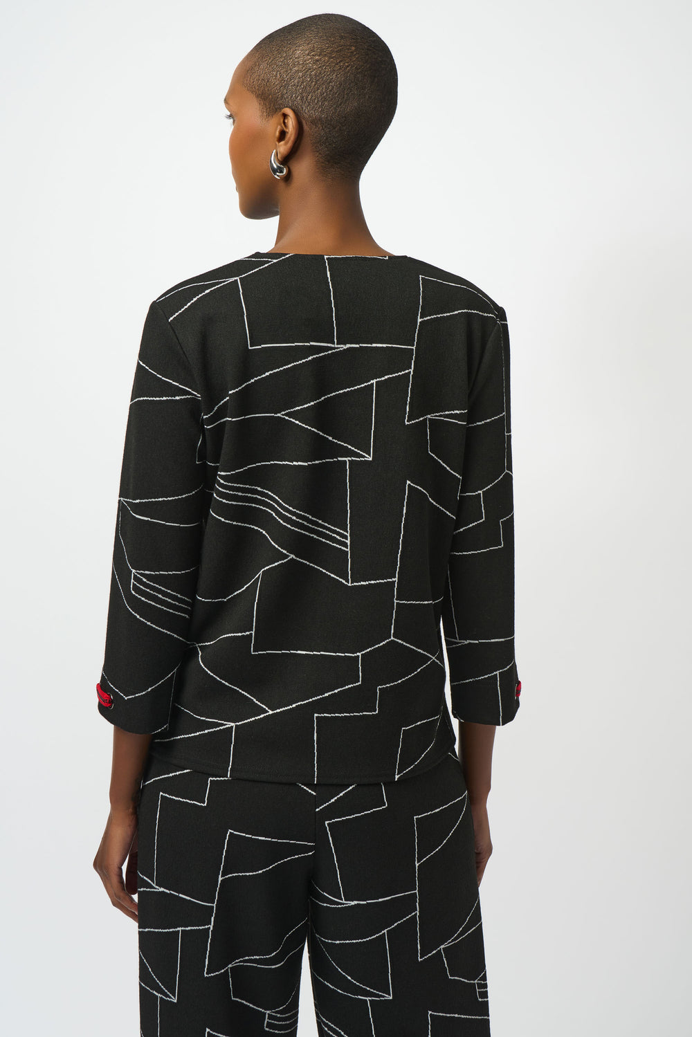 Person wearing a black geometric patterned outfit on a white background