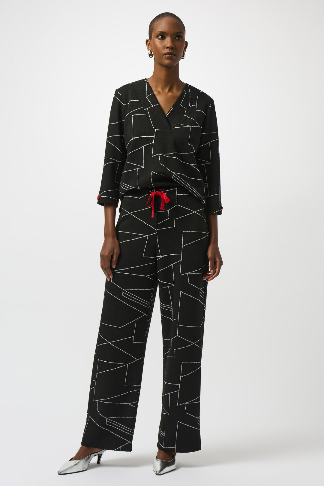 Woman wearing a black geometric patterned outfit with a red belt on a white background