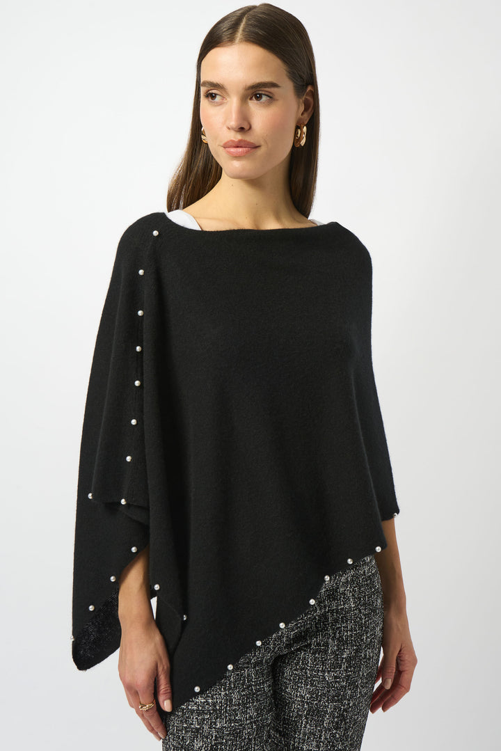 Woman wearing a black poncho with pearl embellishments on a white background