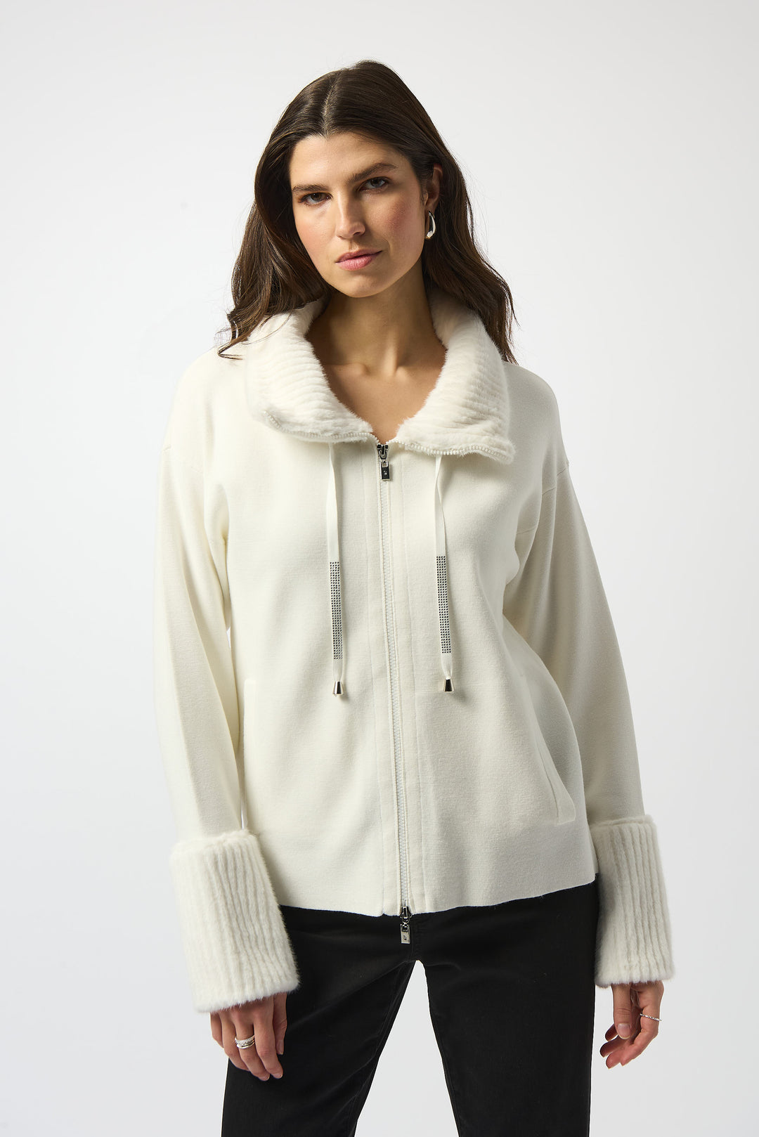 Woman wearing a cream-colored zip-up jacket with faux fur trim on a white background