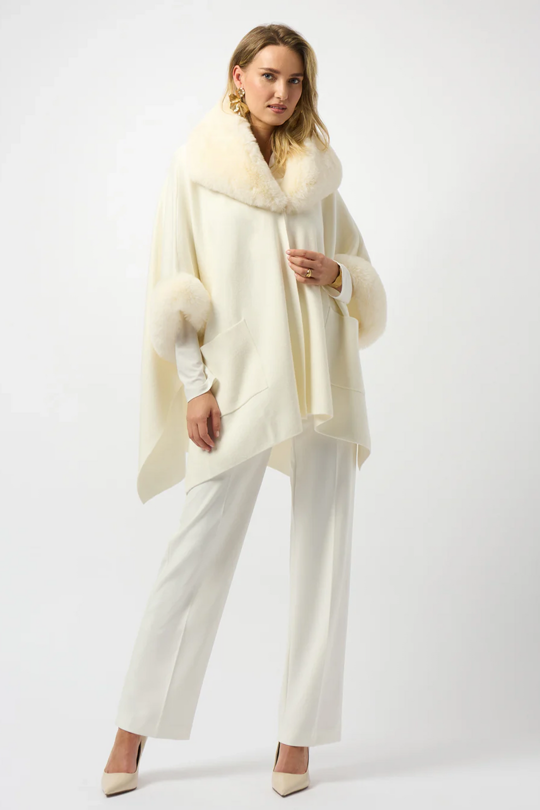 Woman wearing a cream-colored  faux fur-trimmed coat on a white background