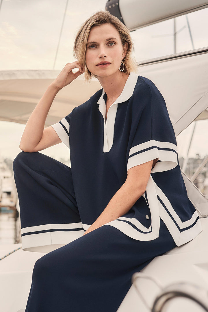 Woman wearing a navy and white light sweater top sitting on a boat.